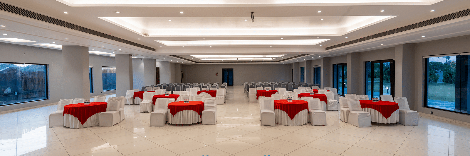 Tables with neatly decorated tablecloths, a plush sofa, and two round tables set in front at DLS Forest Vines Resort.